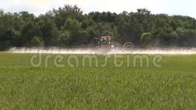 农民用拖拉机喷洒夏季绿色小麦作物<strong>农田</strong>